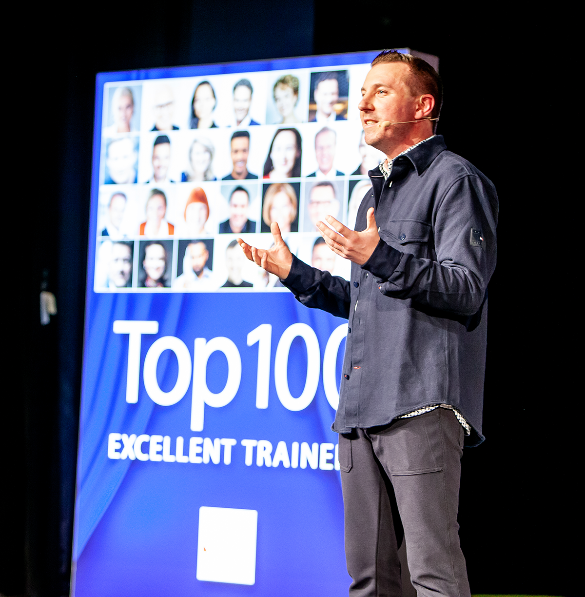 Torsten Schröder steht auf der Bühne vor einem Plakat der Top 100 Excellent Trainer