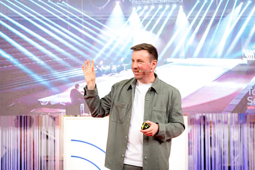 Torsten Schröder steht auf der Bühne und hält seine Keynote, dahinter ist die dazugehörige Präsentation zu sehen