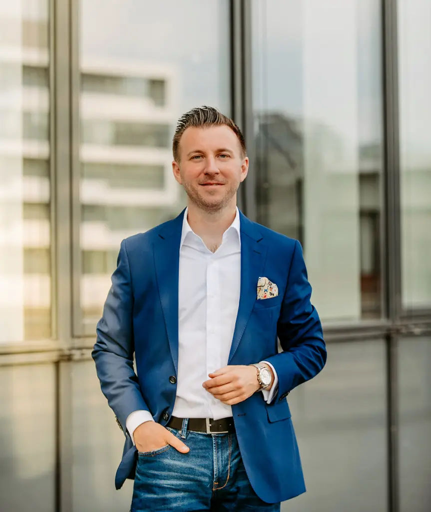 Ein Portrait von Torsten Schröder, welches ihn im Anzug vor einer Fensterwand zeigt