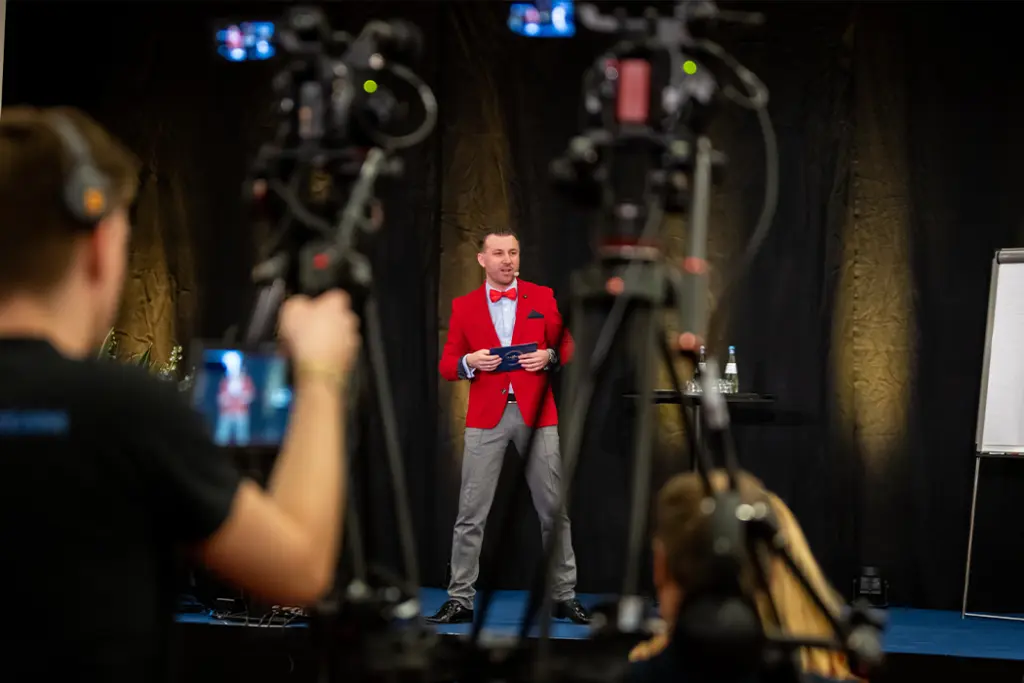 Im Vordergrund stehen zwei Kameras, die Torsten Schröder filmen, in mitten der beiden er auf der Bühne zu sehen ist